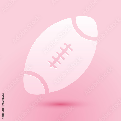 Paper cut American Football ball icon isolated on pink background. Paper art style. Vector.