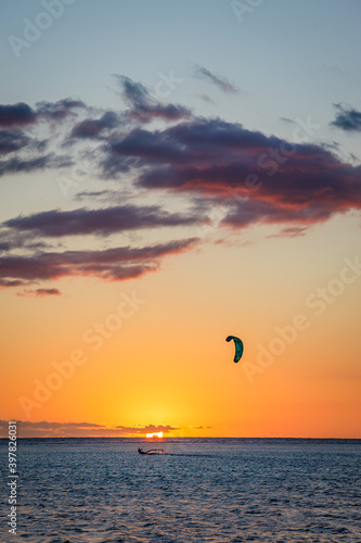 Man kitesurfing at sunset during a beautiful orange sunset on the lagoon of La Saline les Bains in Saint-Gilles on Reunion Island
