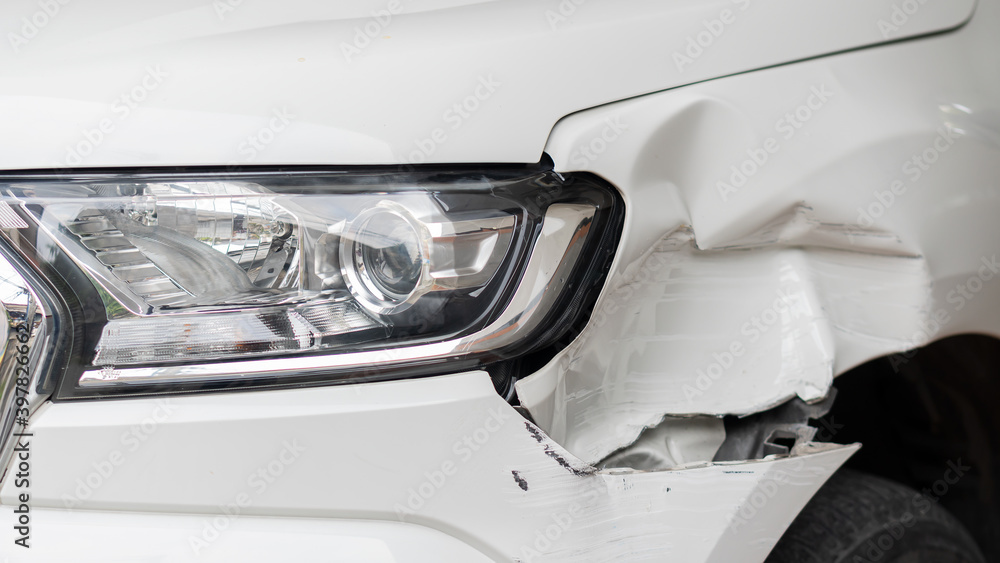 The front light of a white car that was hit in a road accident was damaged.