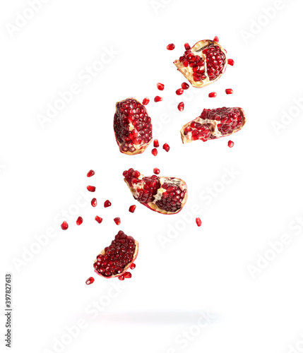 pieces of pomegranate falling, grains and pomegranate slices flying down isolated on white background