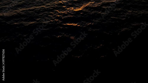 Aerial dolly at sea, tilt up revealing the Sun at sunset photo