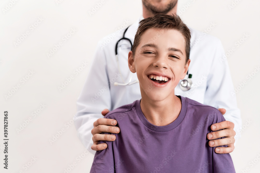 Cropped shot of teenaged disabled boy with cerebral palsy smiling at camera, standing with his male doctor isolated over white background Cropped shot of teenaged disabled boy with cerebral palsy smiling at camera, standing with his male doctor isolated over white background