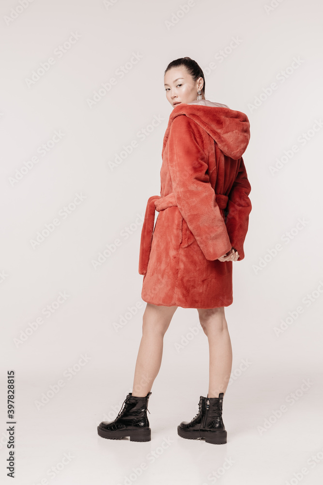 Beautiful and stylish girl with makeup in a fur coat emotionally with a smile posing on a white background Beautiful and stylish girl with makeup in a fur coat emotionally with a smile posing on a white background