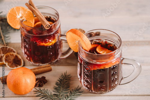 Hot mulled wine with spices in glass cup on wooden background. Christmas warming drink.