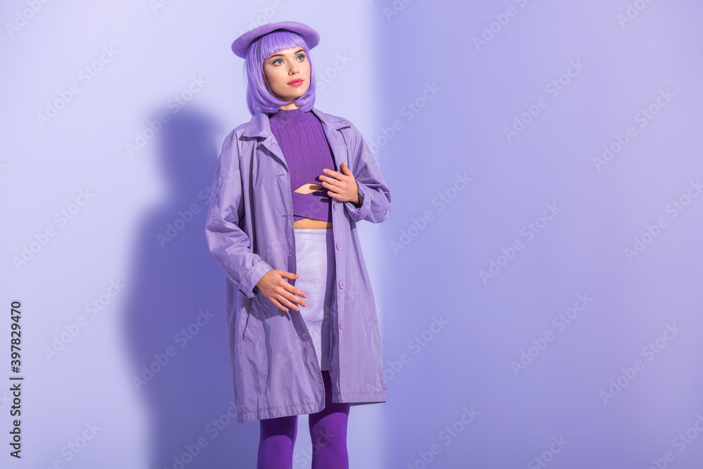 young woman dressed in doll style in beret posing on violet colorful background