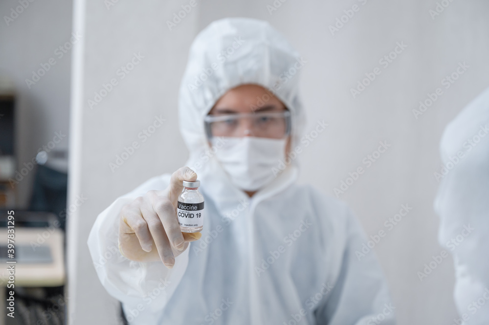 Man researcher in medical ppe showing effective vaccine bottle against Covid-19 in the lab