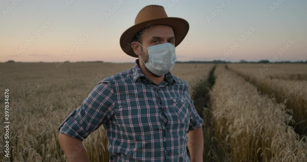 Corona Virus Face Mask Covid-19. Portrait Caucasian Farmer Man in Plaid Shirt in Hat and Looking. Farmer Man in Face Mask for Covid-19 Standing in Wheat Field. Farm Worker. Epidemic Coronavirus. Corona Virus Face Mask Covid-19. Portrait Caucasian Farmer Man in Plaid Shirt in Hat and Looking. Farmer Man in Face Mask for Covid-19 Standing in Wheat Field. Farm Worker. Epidemic Coronavirus.
