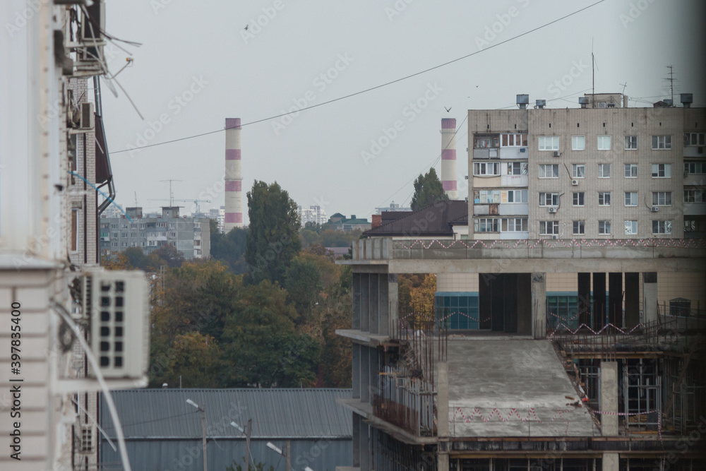 Autumn city landscape. White high-rise building and chimneys of a thermal power plant against a gray sky Autumn city landscape. White high-rise building and chimneys of a thermal power plant against a gray sky