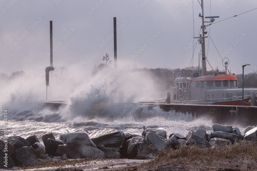 Wellen krachen gegen die Kaimauer am Hafen von Strande, Sturmflut, Ostsee, Winter