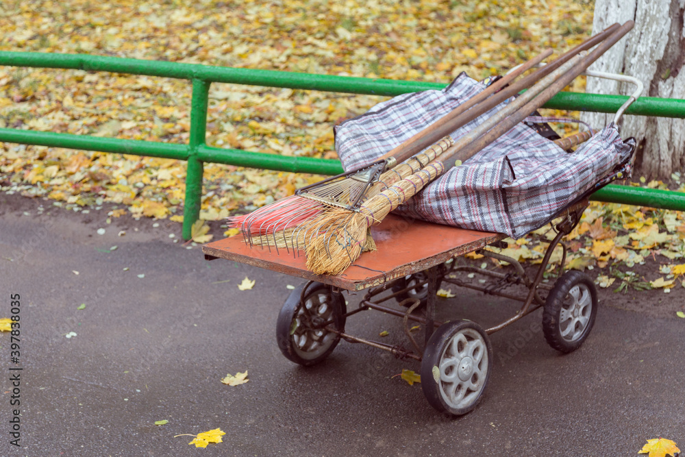 Fototapeta premium Janitor's trolley with a rake and brooms.