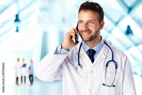 Confident male doctor talking with his patient on mobile phone while standing on the hospital foyer