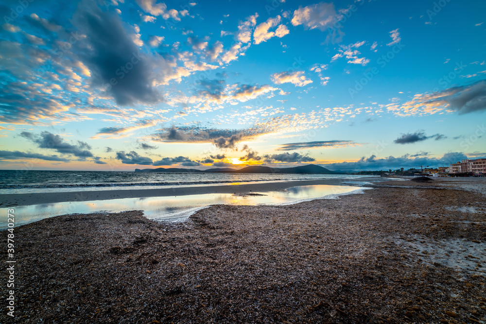 Obraz premium Cloudy sky over Alghero shore at sunset