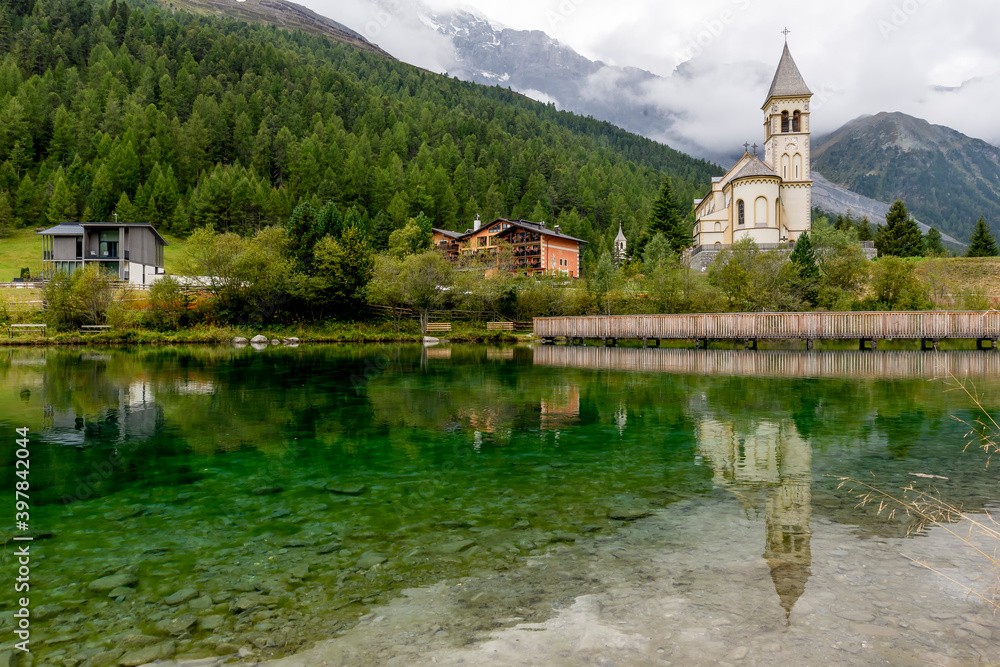 The parish church of Solda, South Tyrol, Italy, is reflected in the water of the lake