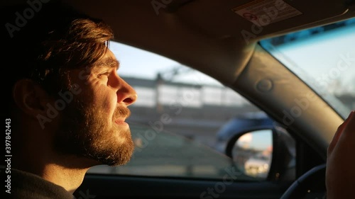Young man driving a car. the setting sun shines in the eyes of the driver.
