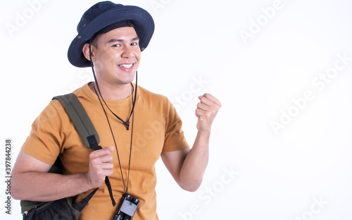 Asian man wearing hat and backpack, standing on white background © Ann Rodchua
