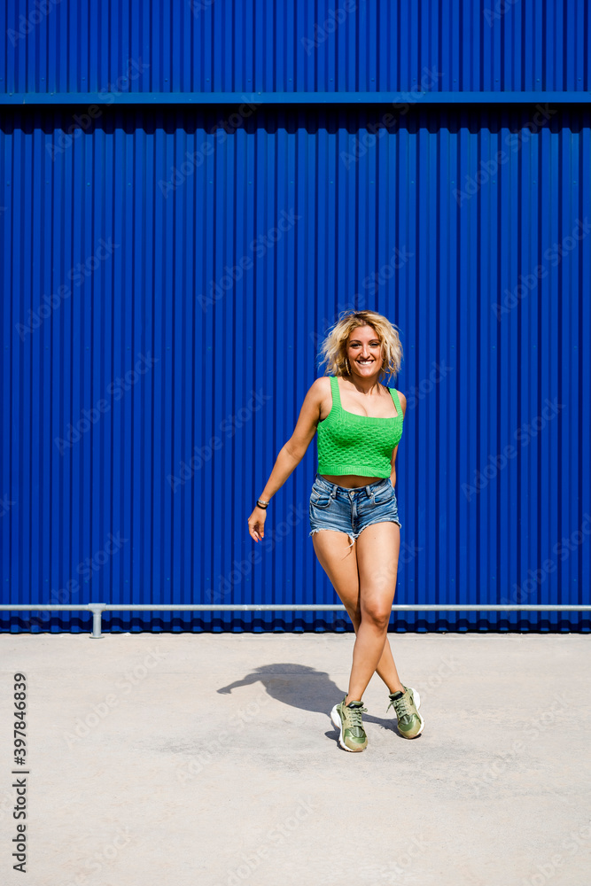 Young woman dancing in front of blue wall in the city