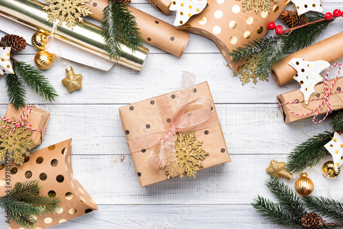 Christmas gift boxes and wrapping paper in gold colors on white wooden background. Copy space for your text. Flat lay and top view