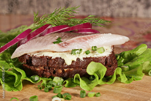 Sandwich with herring. Red onion, rye bread on a brown table.    Tradition Danish open sandwich smorrebrod with herring, egg, cucumber and onions. Dark bread sandwich.  