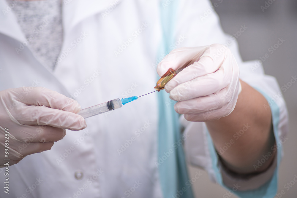 The concept of inoculation, vaccination or treatment of the disease. Close-up of the doctor's gloved hand holding a medical syringe The concept of inoculation, vaccination or treatment of the disease. Close-up of the doctor's gloved hand holding a medical syringe