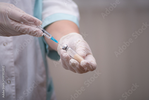 The concept of inoculation, vaccination or treatment of the disease. Close-up of the doctor's gloved hand holding a medical syringe