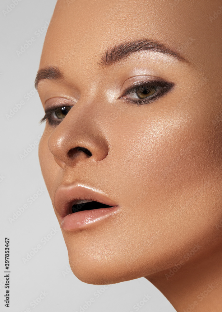 Close-up beautiful young woman with smooth tanned skin. Beauty model with natural bronze make-up, fashion eyeshadows