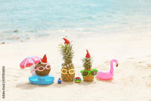 Wallpaper Mural  funny attractive pineapples and coconut in stylish sunglasses on the sand against turquoise sea. Wearing christmas hats.  Torontodigital.ca