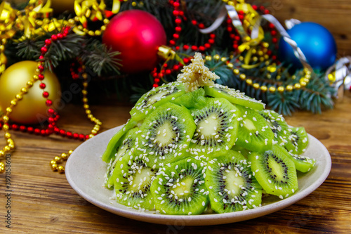 Christmas tree shaped fruit salad and Christmas decorations on wooden table. Creative idea for Christmas and New Year festive desserts. Funny food idea for kids