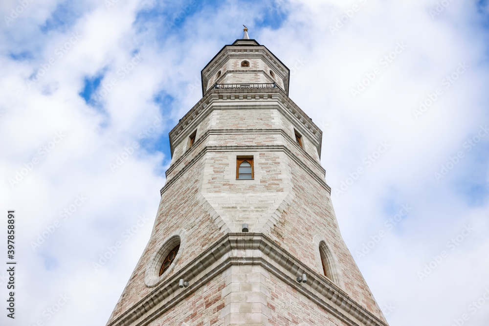 beautiful church stone tower in gothic style against a blue sky with clouds