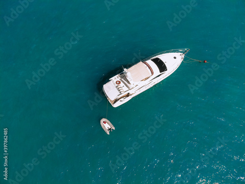 Adorable aerial top view photo of a laxury huge two-storey yach and a small boat next to it sailing across the deep blue sea © Semachkovsky 