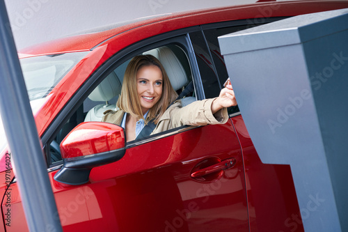 Woman getting ticket from parking meter in underground parking © Kalim