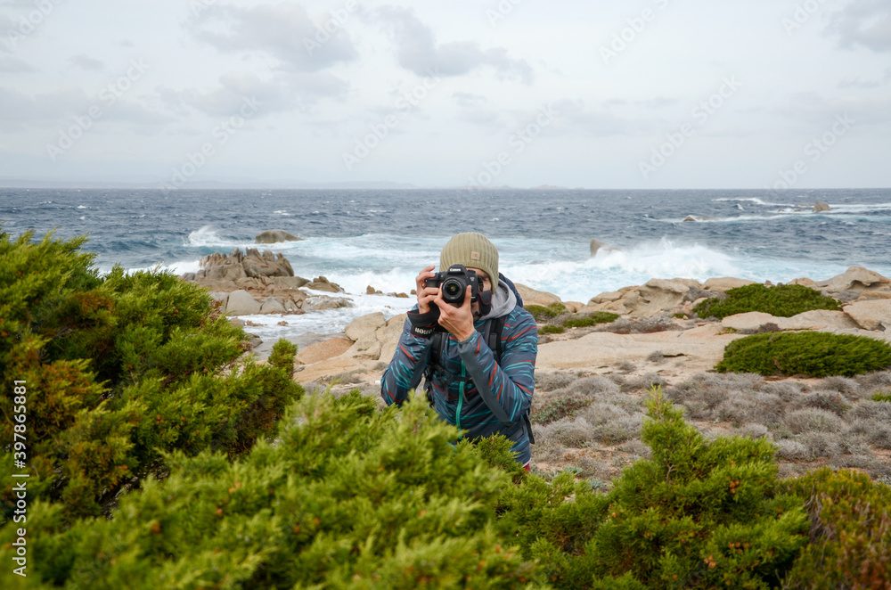 person taking photo of the camera on the beach, behind the sea