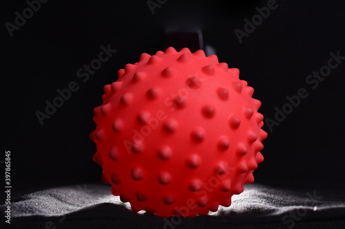 red colorful bright isolated spiky ball toy on a black background, macro