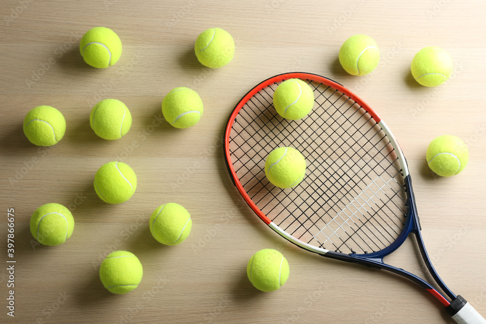 Tennis racket and balls on wooden table, flat lay. Sports equipment