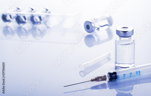 Vial with liquid drug as vaccine dose flu shot along with syringe for injection treatment on medical table. Vaccination or immunization care concept background.