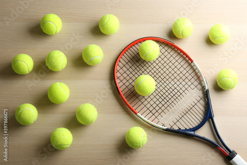 Tennis racket and balls on wooden table, flat lay. Sports equipment