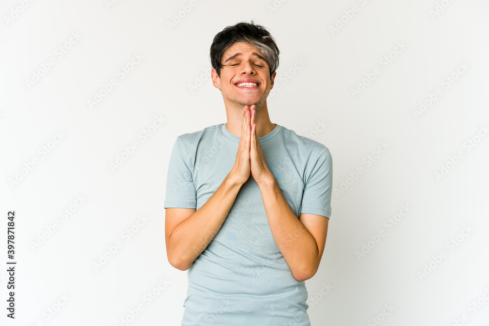 Young skinny hispanic man holding hands in pray near mouth, feels confident.