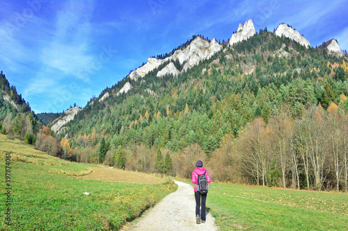 Backpacker woman hiking on the country road. Beautiful nature around them. Outdoor activity and walking in the Pieniny mountains.
