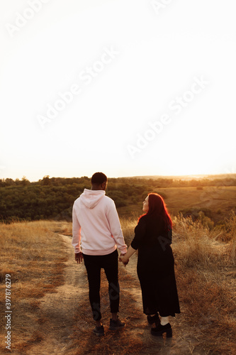 Wonderful couple walking at the field, African American man holding hands lovely white woman, attractive husband with adorable wife spend time together, weekends outdoors concept