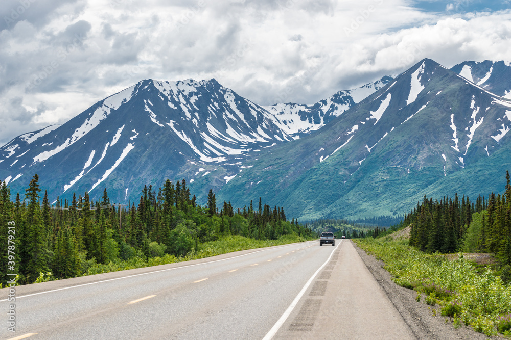 Car on Alaskan Road in Summer headed to Mountains
