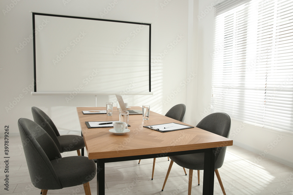 Conference room interior with wooden table and video projection screen Conference room interior with wooden table and video projection screen