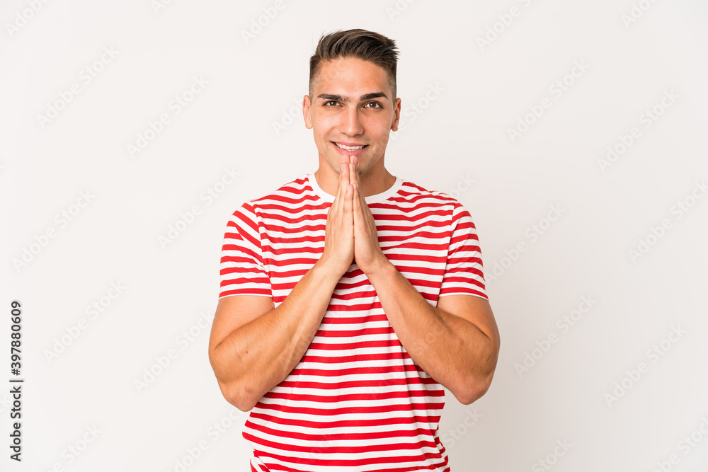 Young caucasian handsome man isolated holding hands in pray near mouth, feels confident. Young caucasian handsome man isolated holding hands in pray near mouth, feels confident.