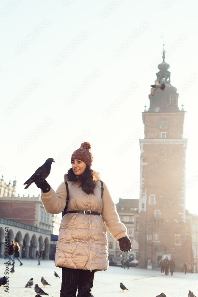 Fototapeta premium Young woman and pigeons in Market Square, Krakow, Poland