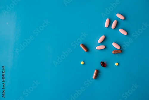 Different colors medical pills on blue background with copy space. 
