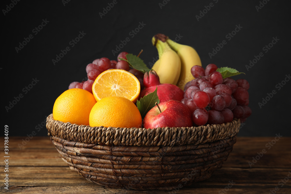 Wicker basket with different fruits on wooden table, closeup Wicker basket with different fruits on wooden table, closeup