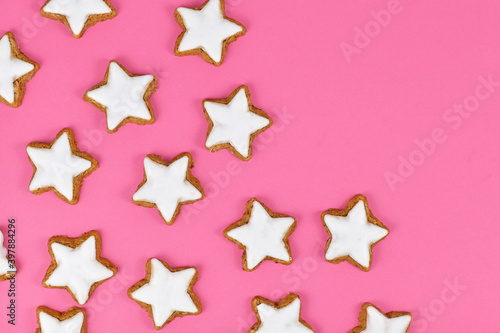 German star shaped glazed cinnamon Christmas cookies called  Zimtsterne  on pink background