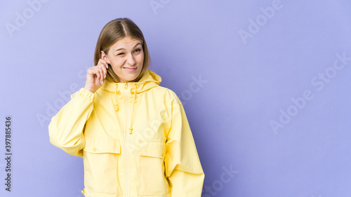 Young blonde woman isolated on purple background covering ears with fingers, stressed and desperate by a loudly ambient.