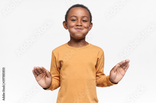 Portrait of funny dark skinned boy fooling around having mouth full of water, can not say anything, trying to be serious, going to burst out laughing. Joy, happiness, laughter and positive emotions