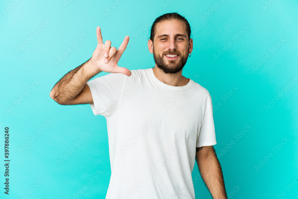 Young man with long hair look showing a horns gesture as a revolution concept. Young man with long hair look showing a horns gesture as a revolution concept.