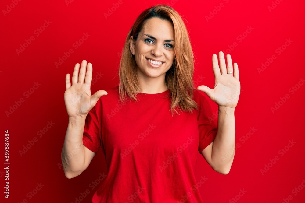 Hispanic young woman wearing casual red t shirt showing and pointing up with fingers number ten while smiling confident and happy. Hispanic young woman wearing casual red t shirt showing and pointing up with fingers number ten while smiling confident and happy.