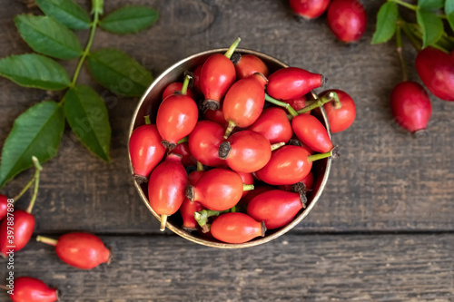 Fresh rose hips in a bowl on a table, top view